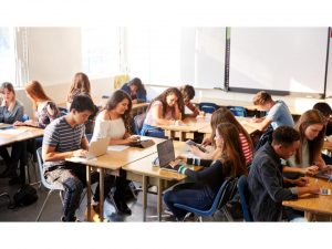 Photo d'une classe placée en ilôts, avec des étudiants.